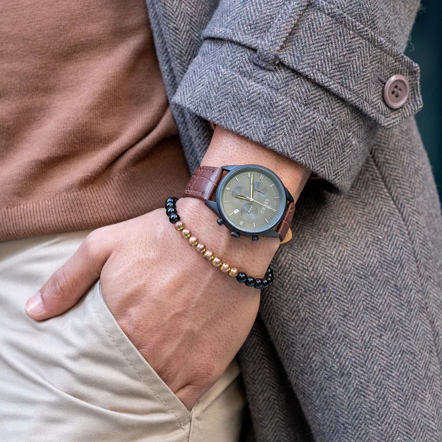 Combe Chronograph worn on a wrist in a herringbone coat, olive sunburst dial on a brown calf strap