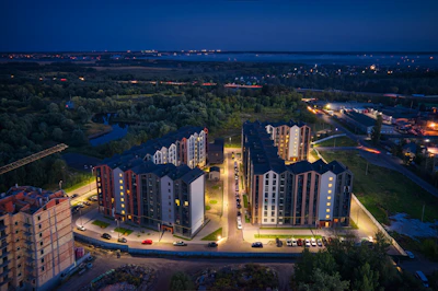 Night view of a grand residential complex with illuminated facades and landscaped gardens