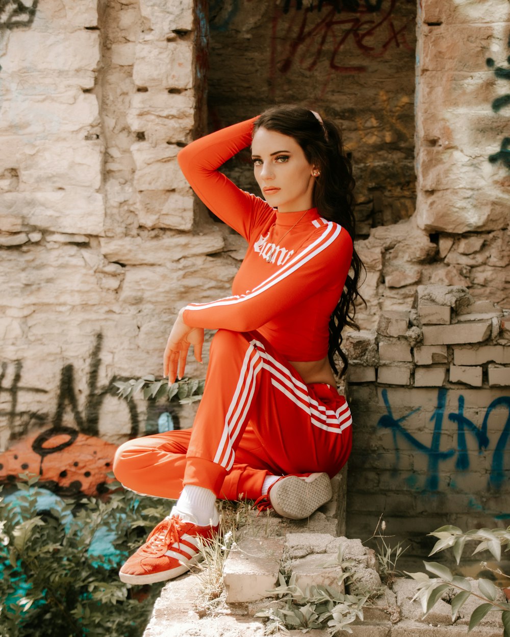 woman in red sleeveless dress sitting on concrete wall