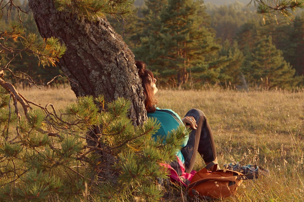 femme en chemise bleue assise sur le champ d’herbe marron et vert pendant la journée