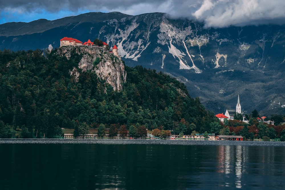 white and red house near body of water and mountain