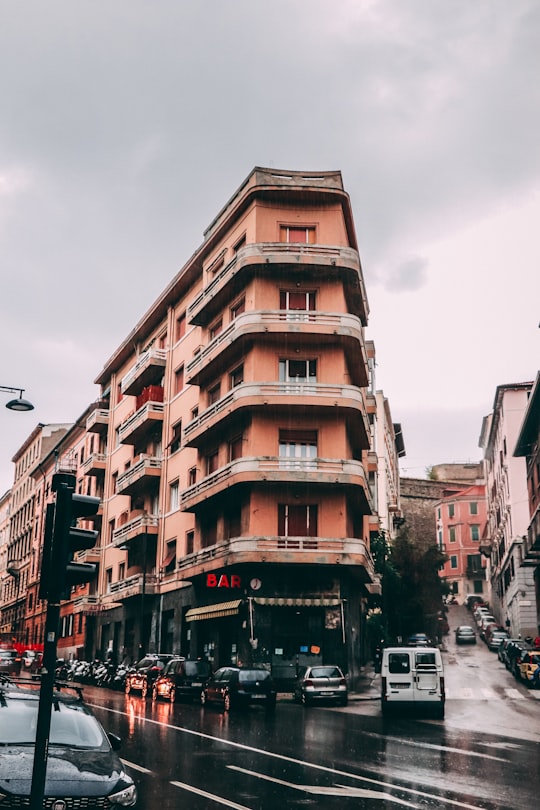 cars parked in front of brown concrete building during daytime in Trieste Italy