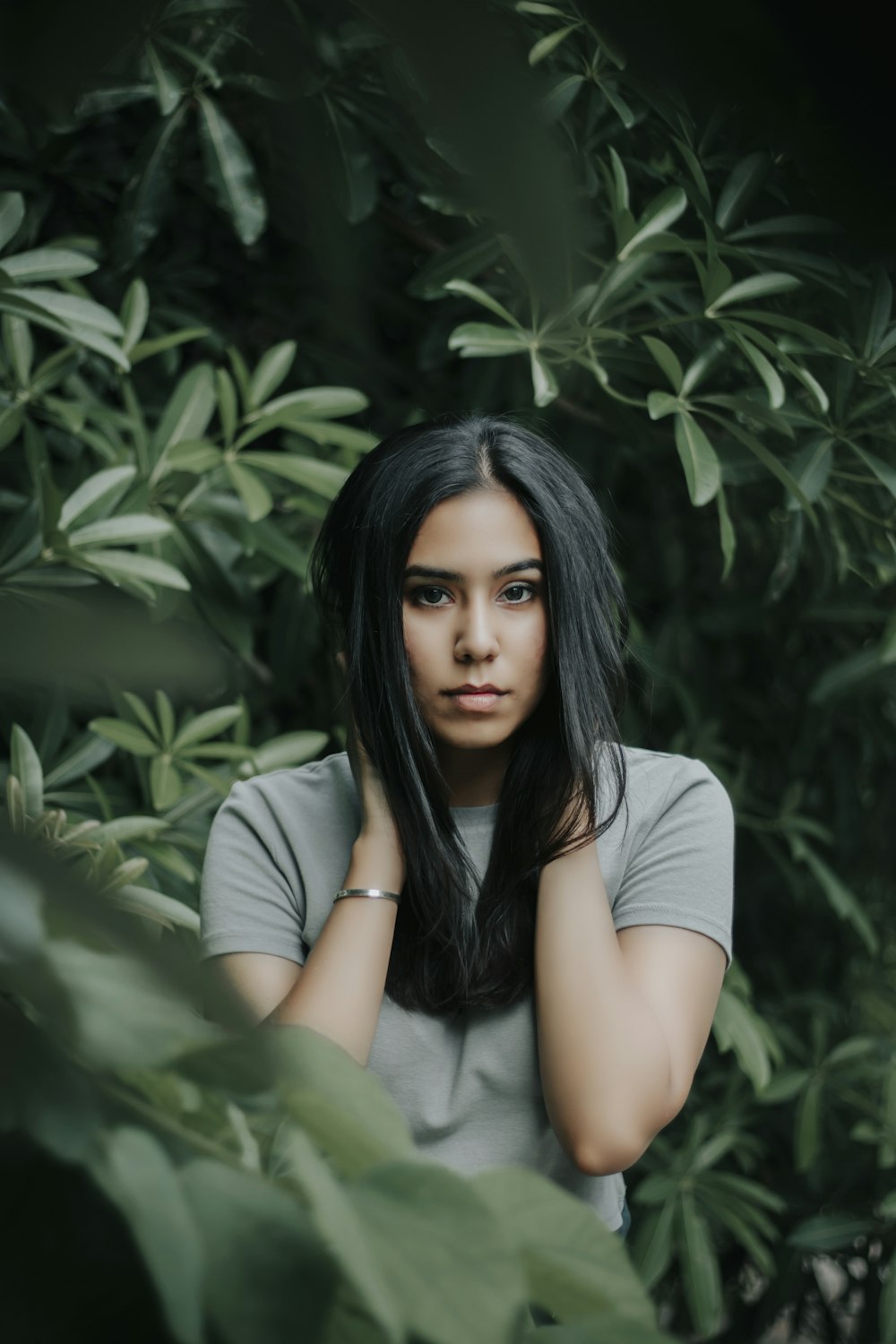 woman in white t-shirt sitting beside green plant