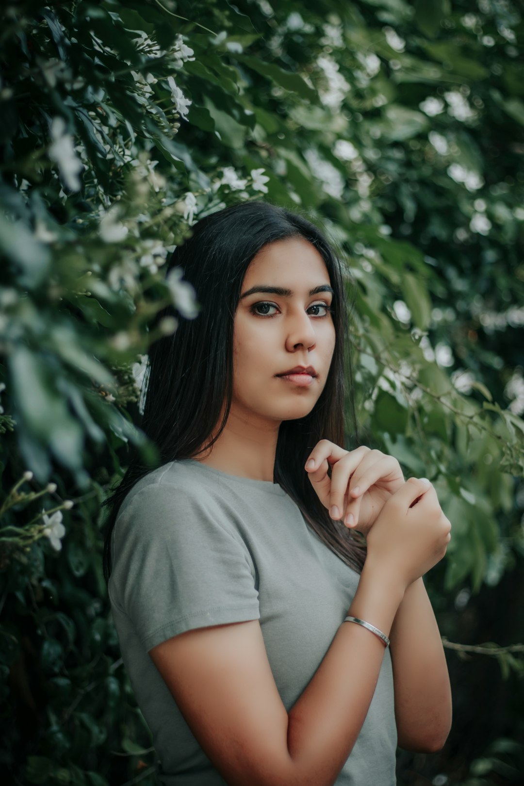 woman in gray crew neck t-shirt standing near green tree during daytime