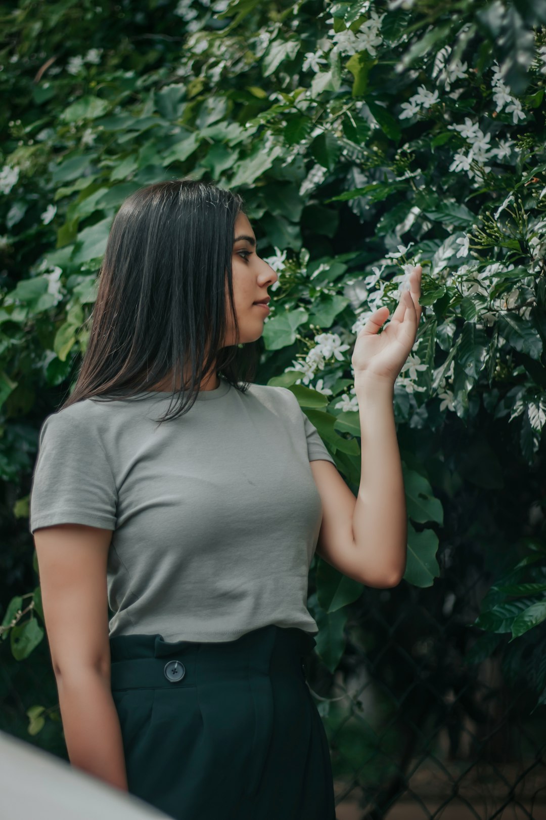 woman in gray t-shirt standing near green leaf plant during daytime