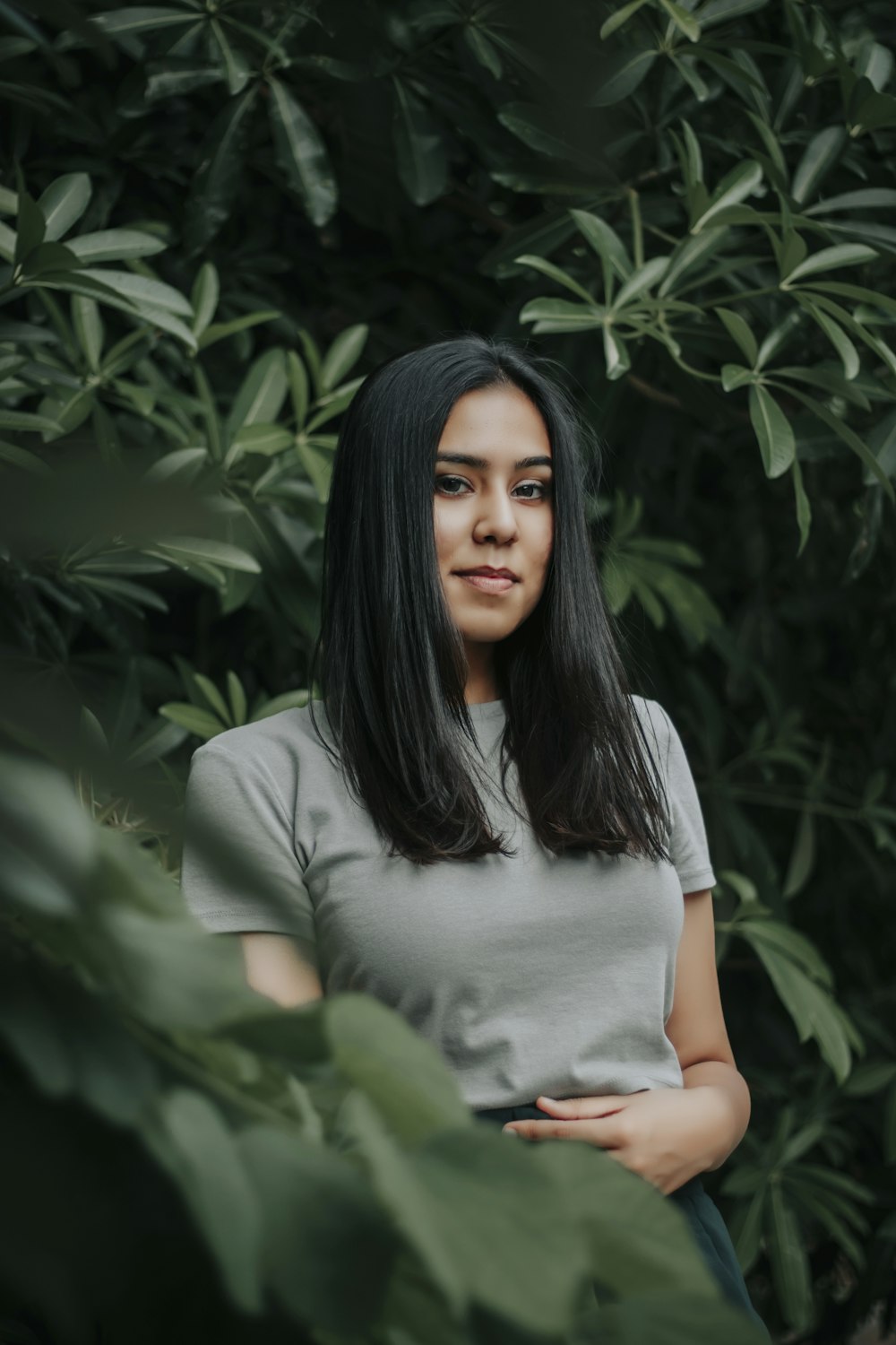 woman in white t-shirt standing near green plant