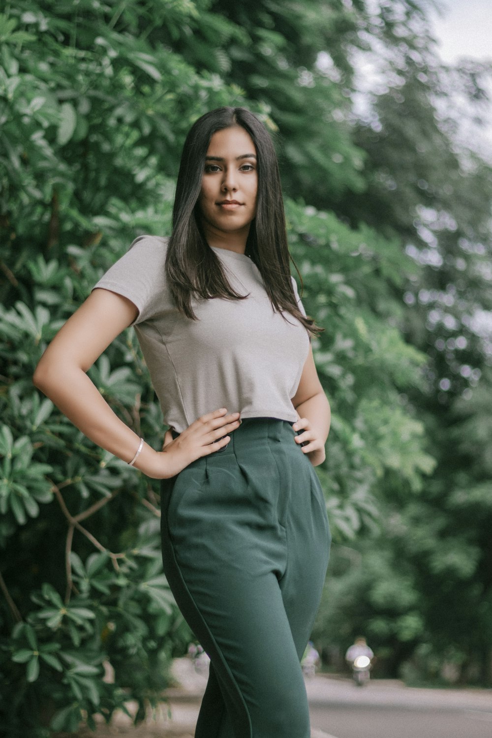 woman in white t-shirt and blue denim jeans standing near green plants during daytime