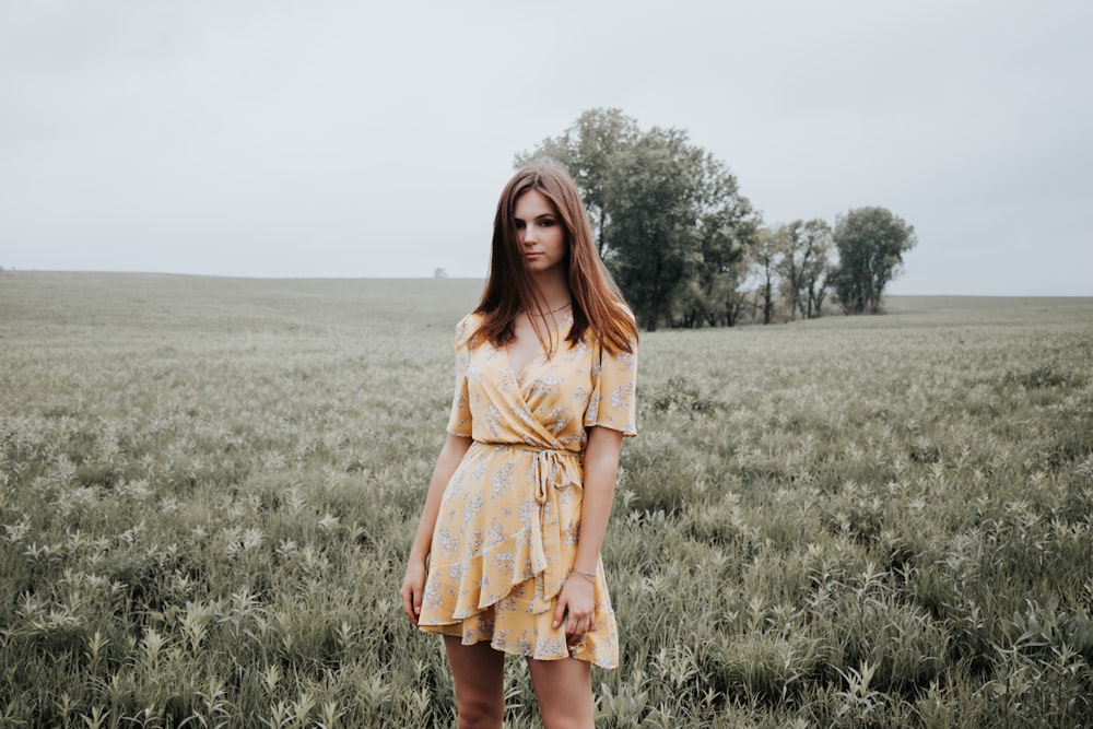 Frau in gelbem Kleid tagsüber auf grünem Rasen steht