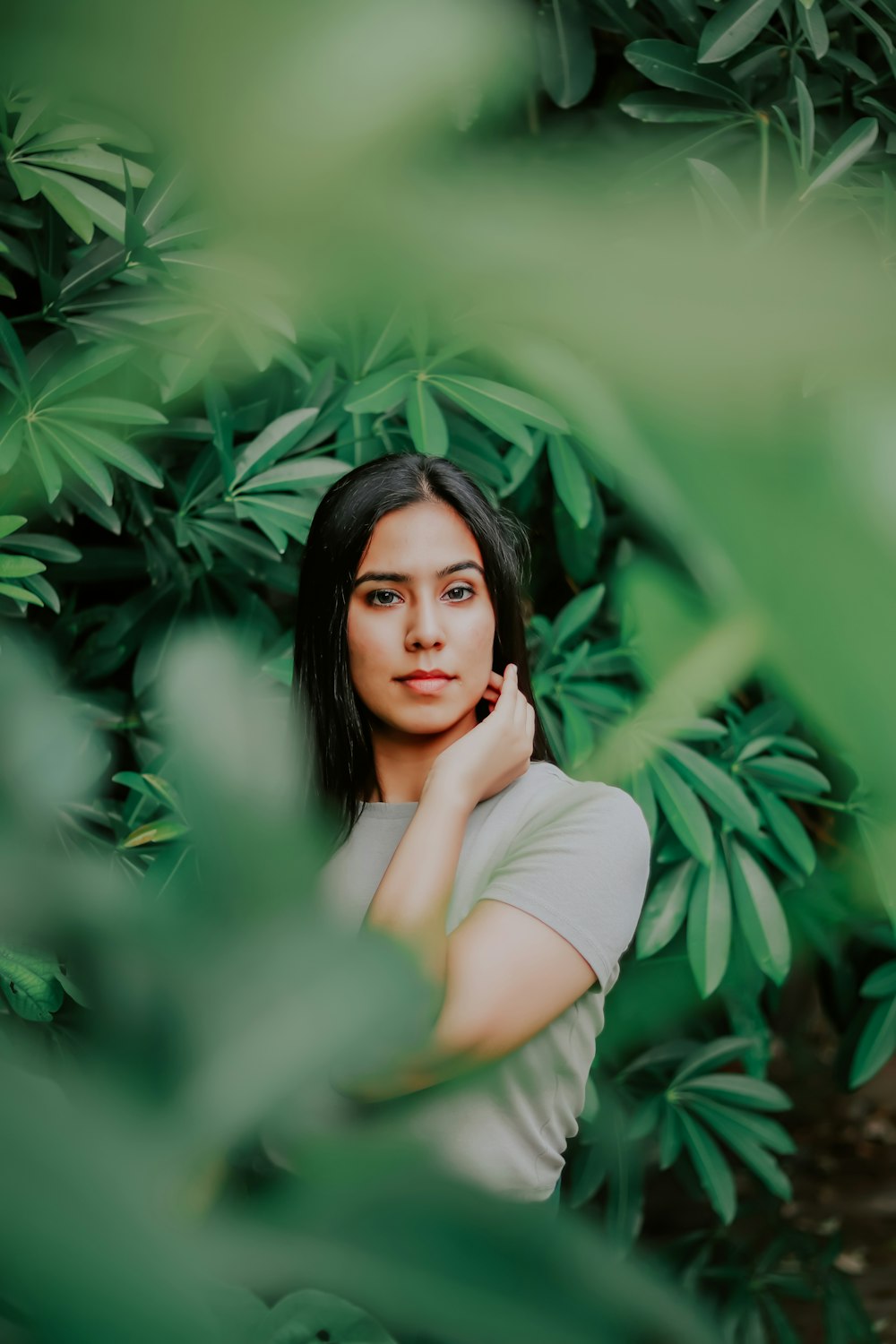 woman in white long sleeve shirt standing beside green plant