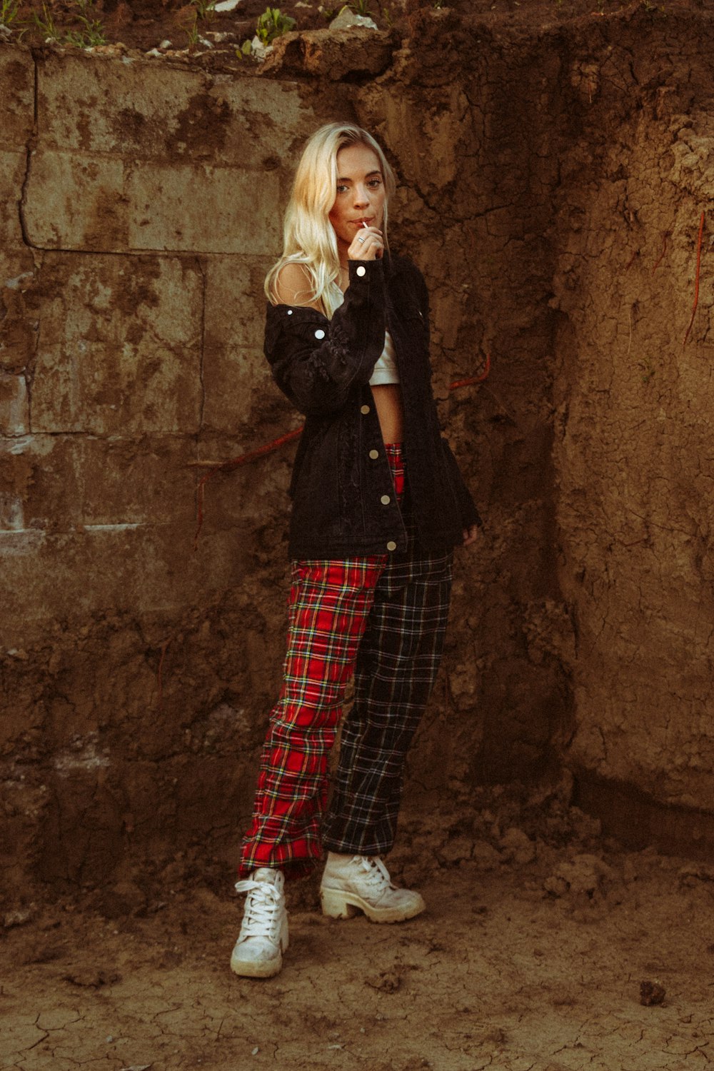 woman in black long sleeve shirt and red and white plaid pants standing beside brown concrete