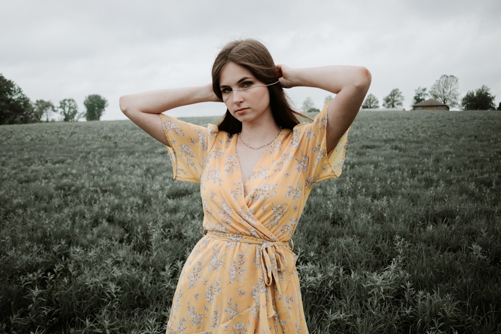 woman in yellow floral dress standing on green grass field during daytime