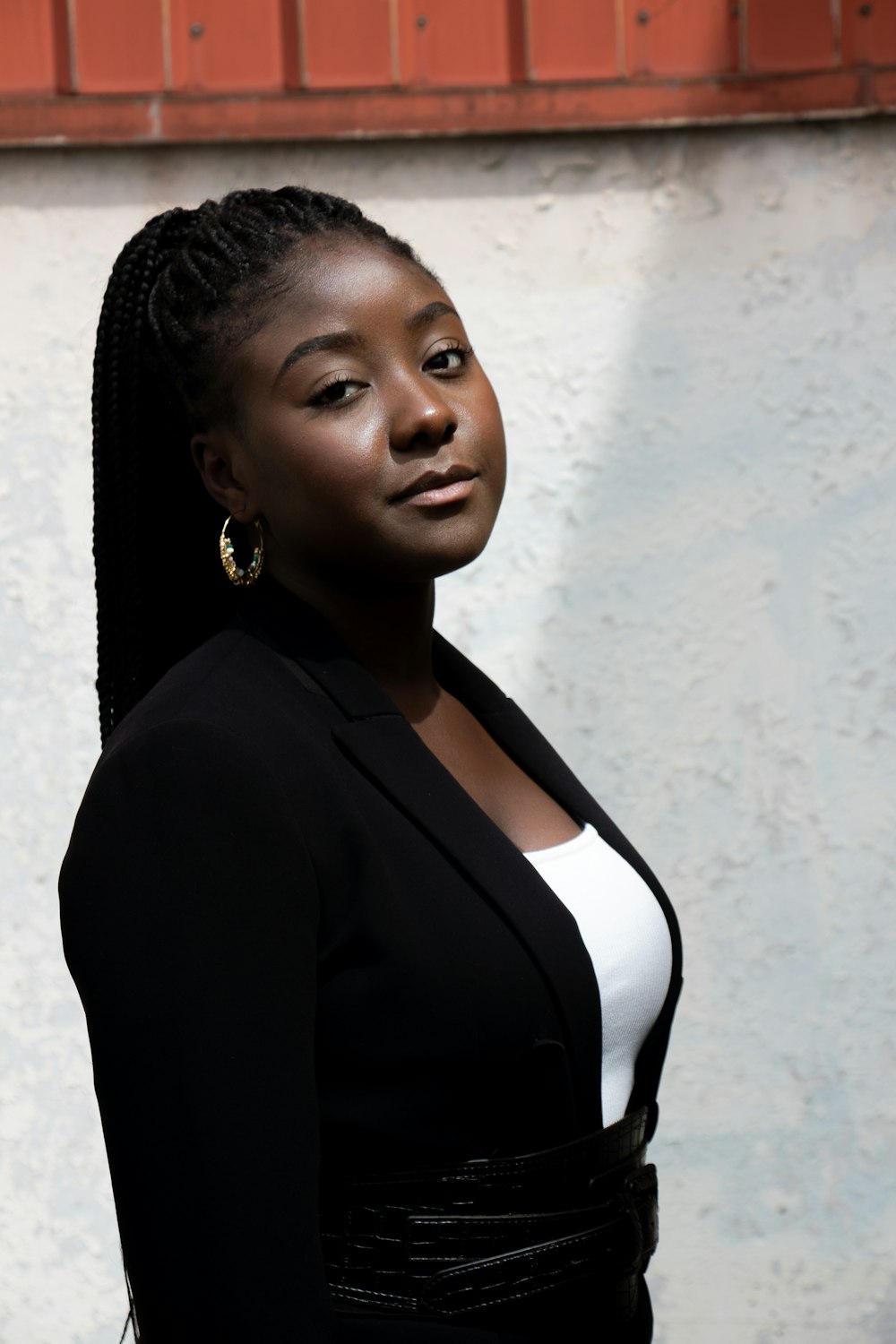 woman in black blazer standing near white wall