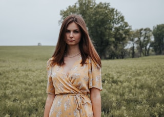 woman in yellow floral dress standing on green grass field during daytime