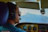Close-up of a pilot wearing sleek Aerovista smart glasses against a backdrop of a cockpit and blue sky.