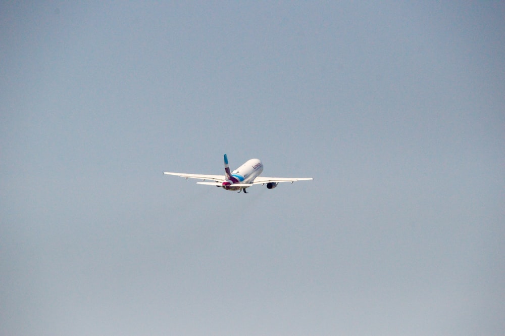white and blue airplane flying during daytime
