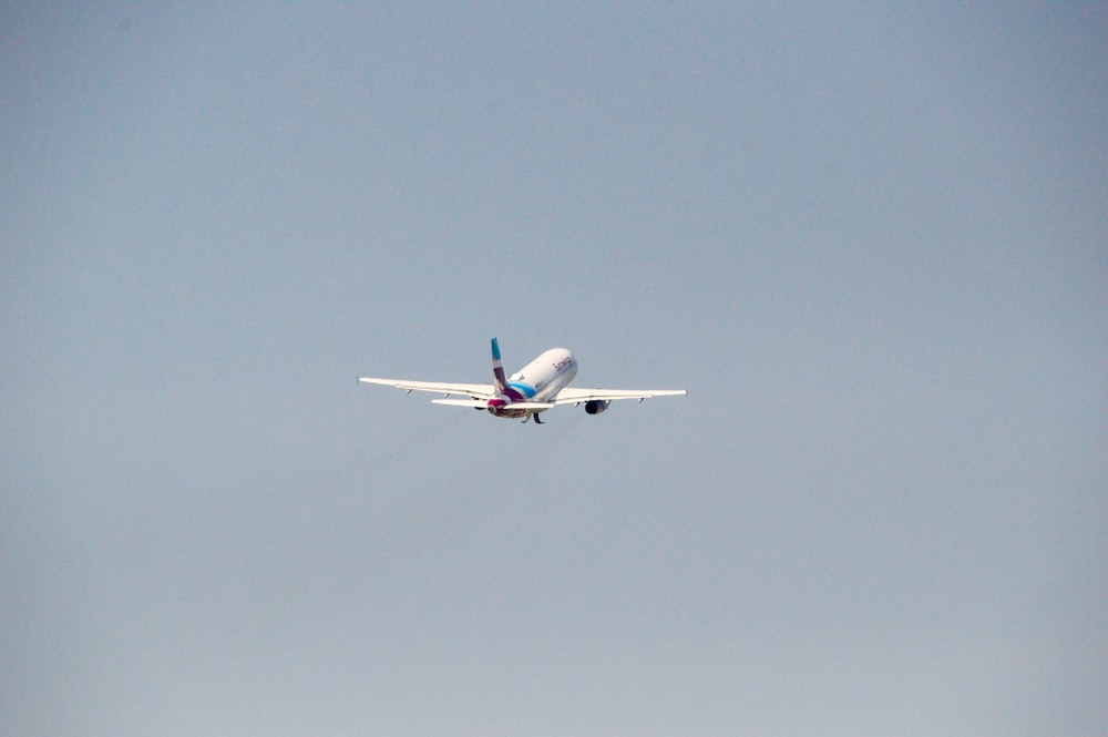 avião branco e azul voando durante o dia