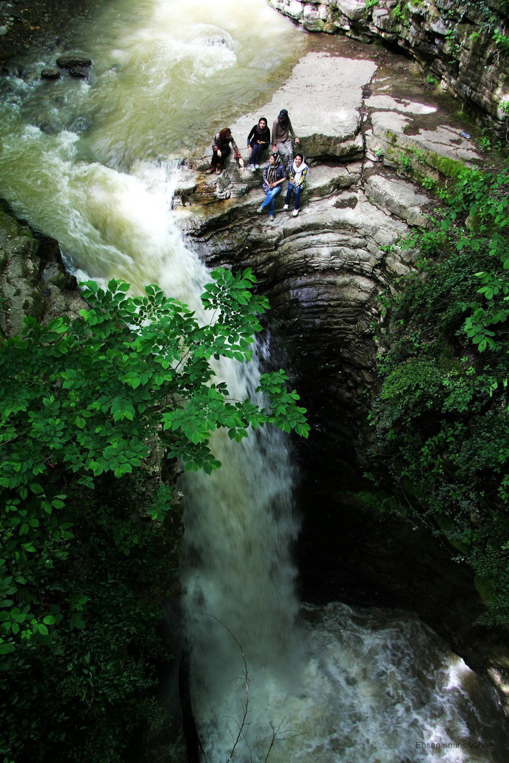 people sitting on rock near waterfalls during daytime