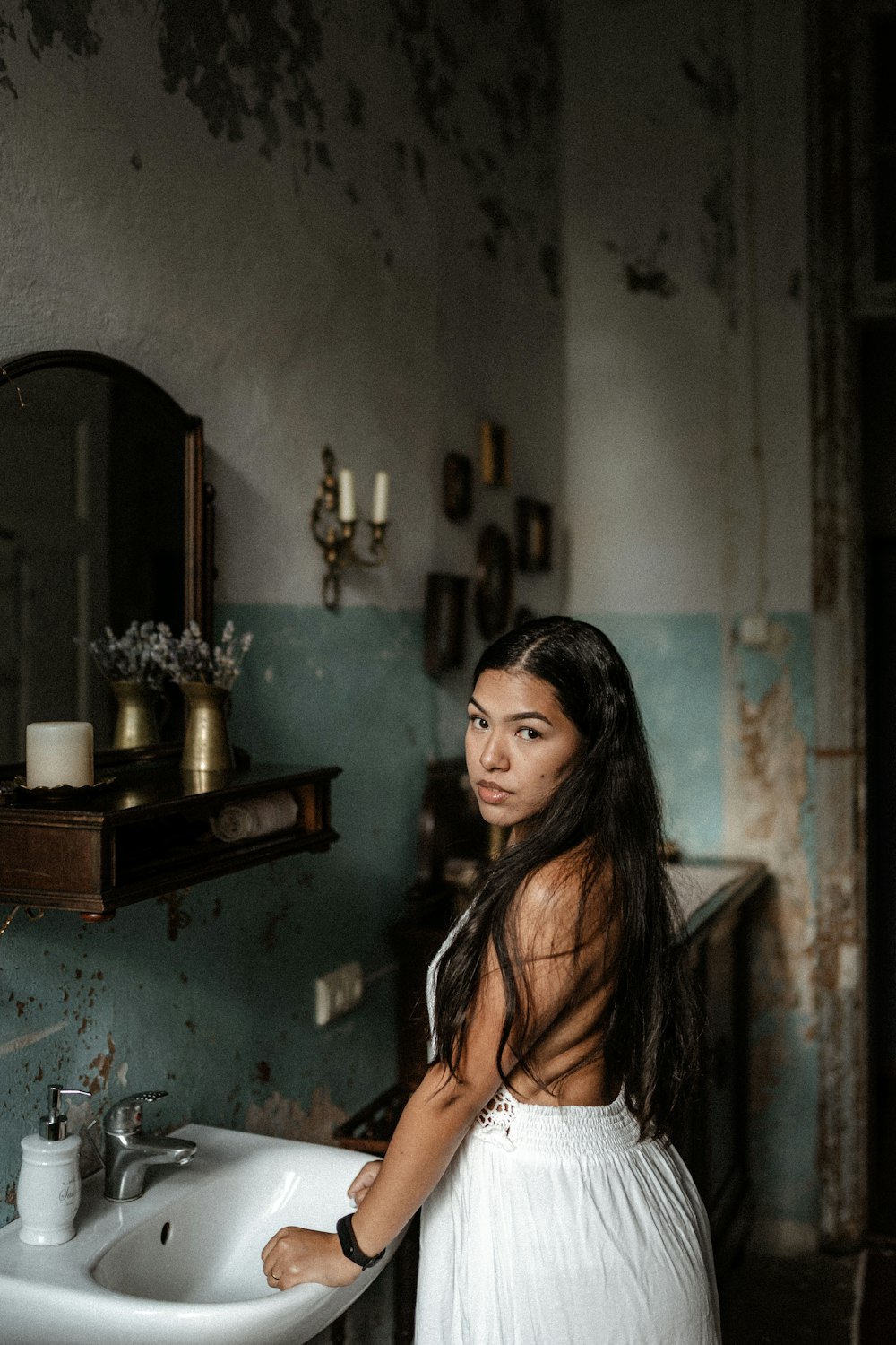 woman in white tank top standing beside brown wooden table