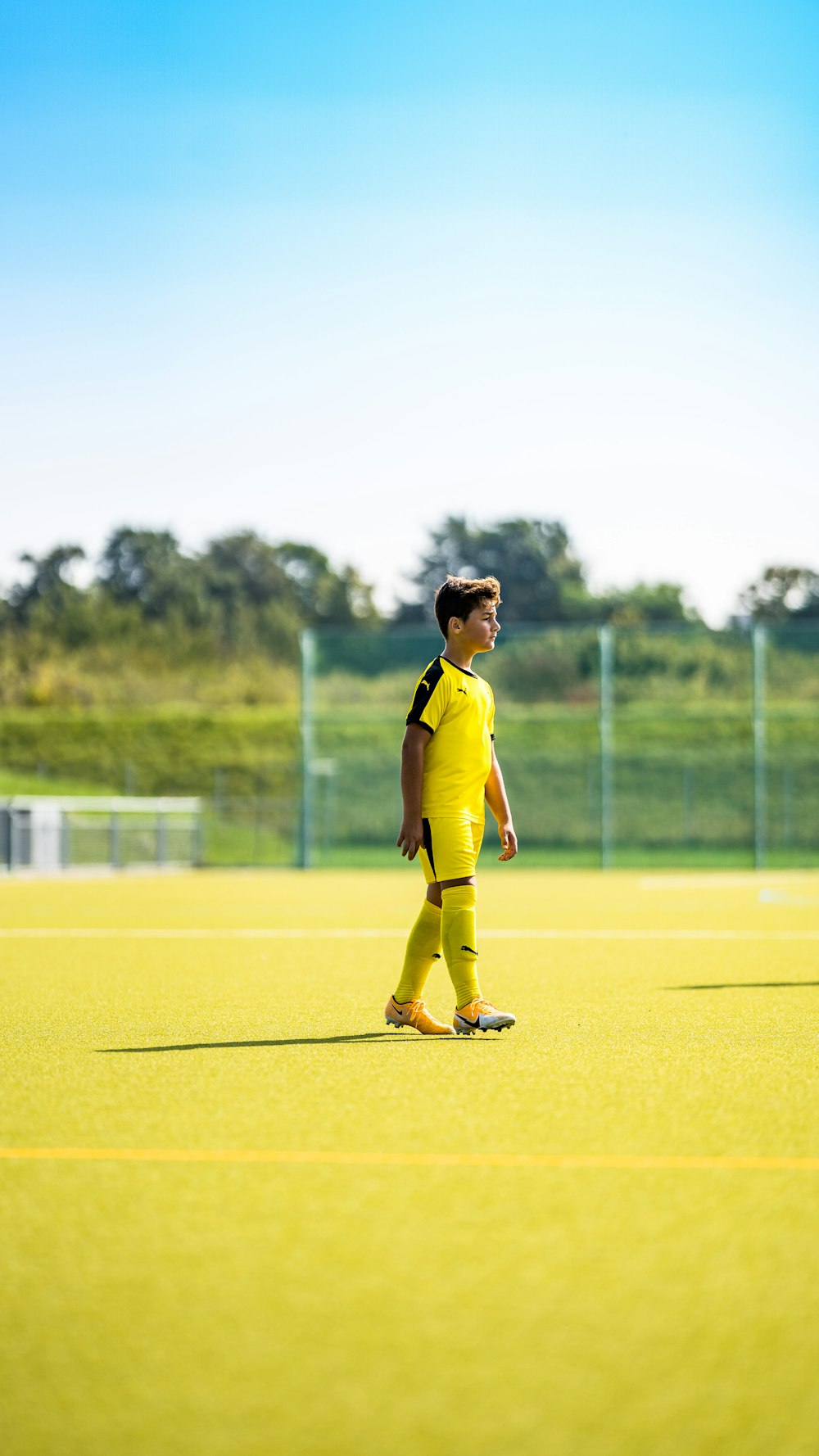 woman in yellow long sleeve shirt and yellow pants standing on green grass field during daytime