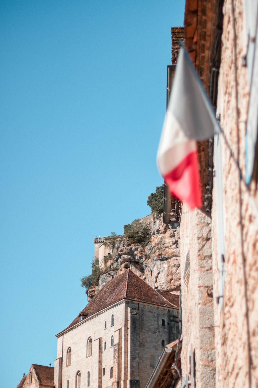 white and red flag on brown rock formation under blue sky during daytime