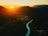 Aerial shot of a lush Ecuadorian landscape with mountains and rivers at sunset.