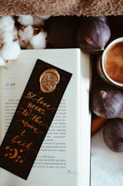 An open book surrounded by whimsical bookish accessories like bookmarks and pins.