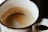 Close-up of a coffee cup with crema on top on a wooden table.
