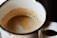 Close-up of a coffee cup with crema on top on a wooden table.