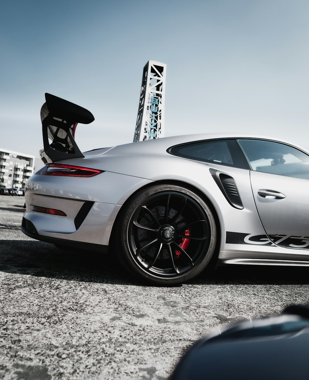 Porsche 911 blanco y negro estacionado sobre pavimento de concreto gris durante el día