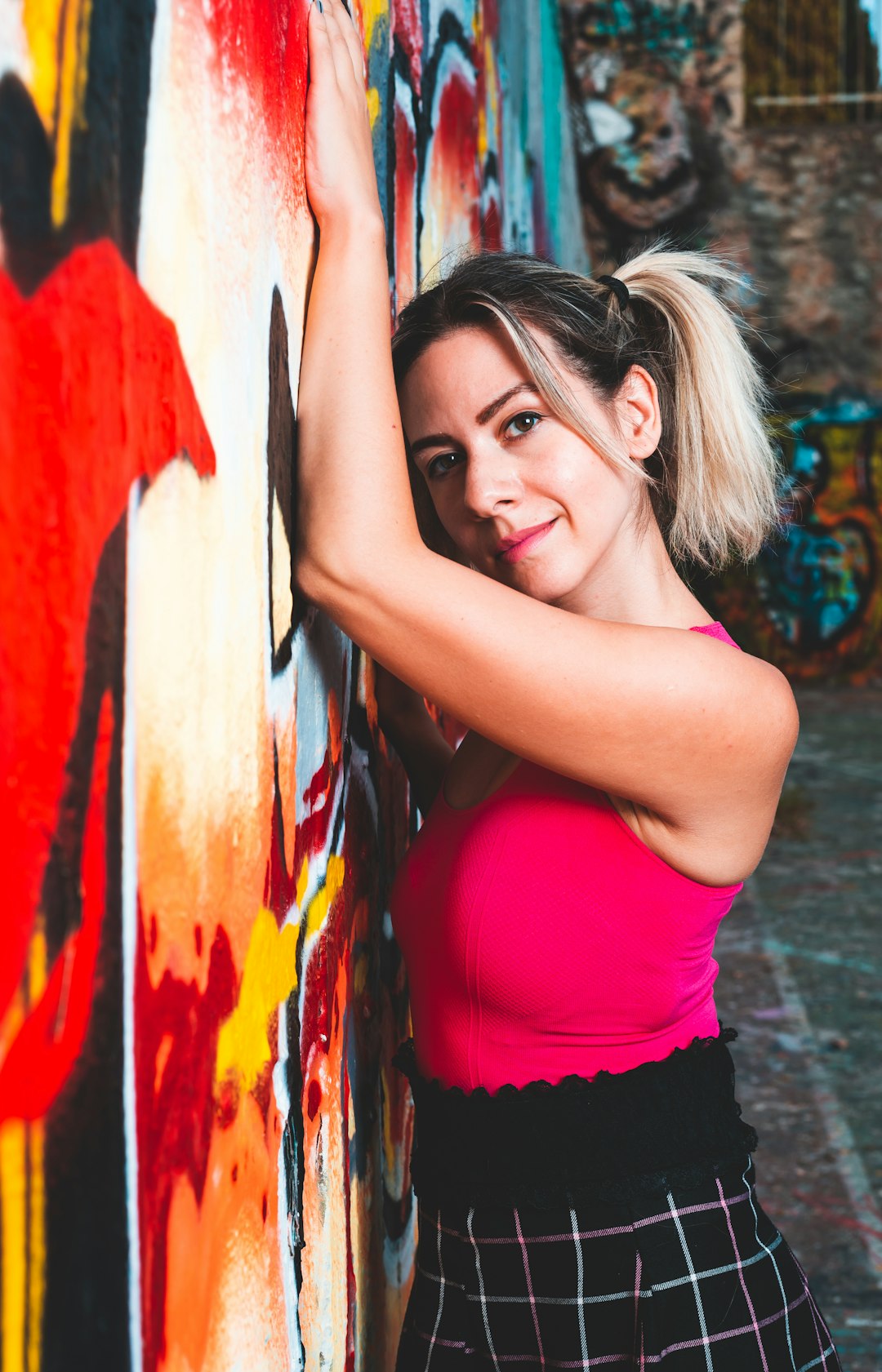 woman in red tank top leaning on wall