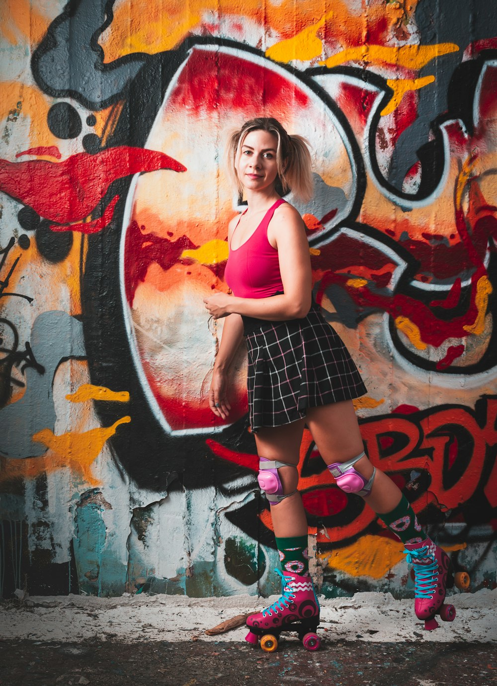 Frau in lila Tanktop und schwarz-weiß kariertem Rock an der Wand mit Graffiti