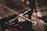 Close-up of a hand-forged sword resting on a rugged wooden workbench with soft, moody lighting.