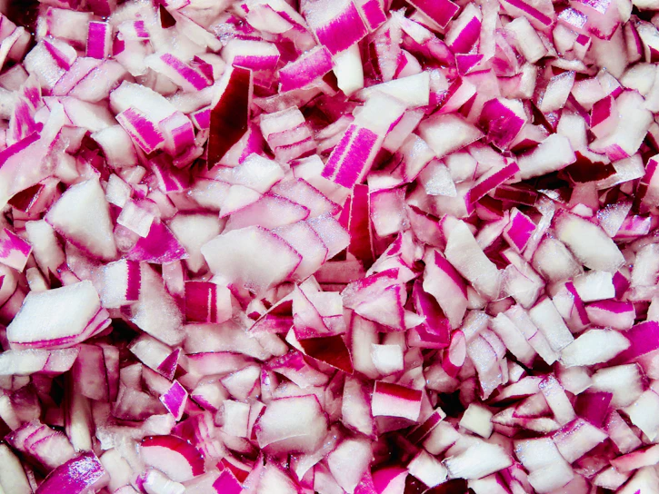 A close-up shot of dehydrated onion flakes spread out on a vibrant wooden surface, showcasing their texture and quality.