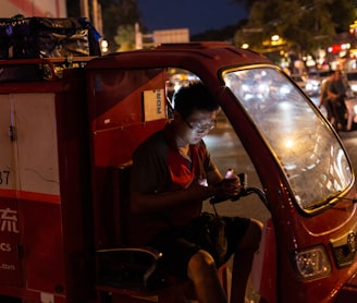 man in red polo shirt sitting on red car