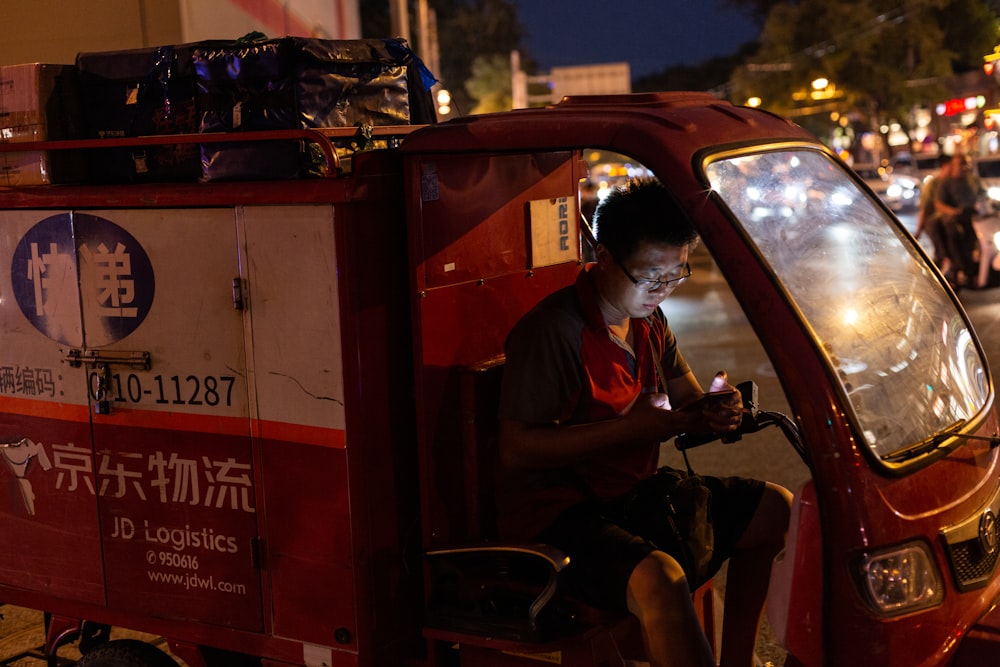 man in red polo shirt sitting on red car