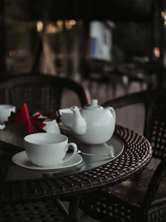 A close-up of a delicate miniature tea set arranged on a tiny wooden table.