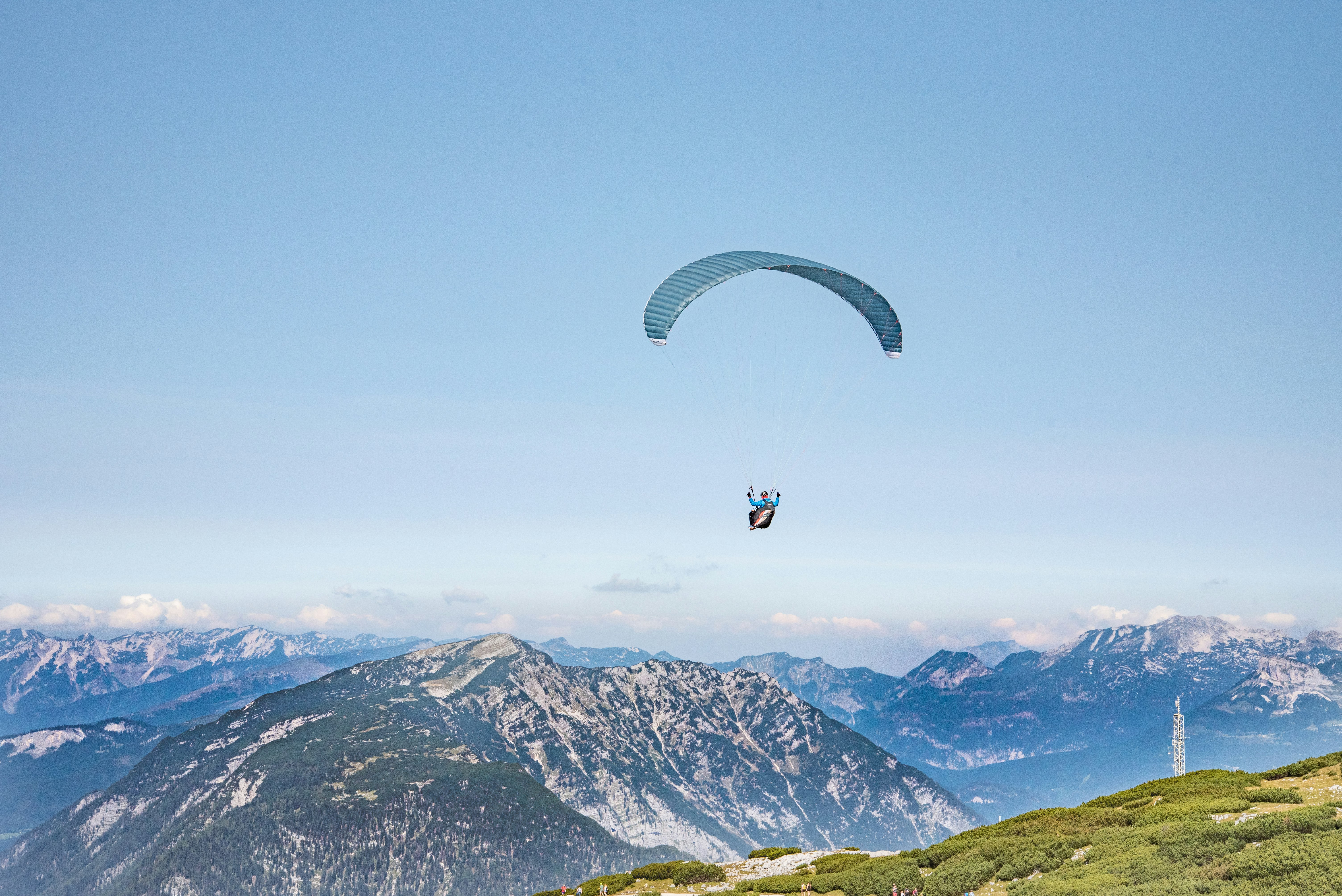 person riding parachute over green and brown mountains during daytime
