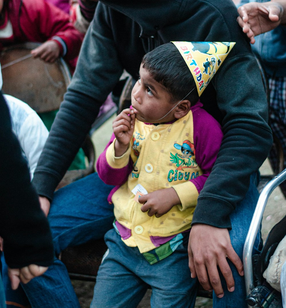 man in black jacket holding baby in yellow shirt