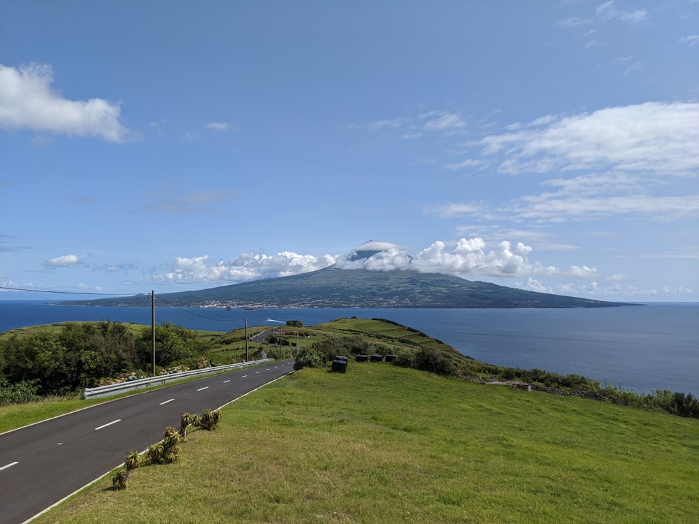 gray asphalt road near green grass field under blue sky during daytime