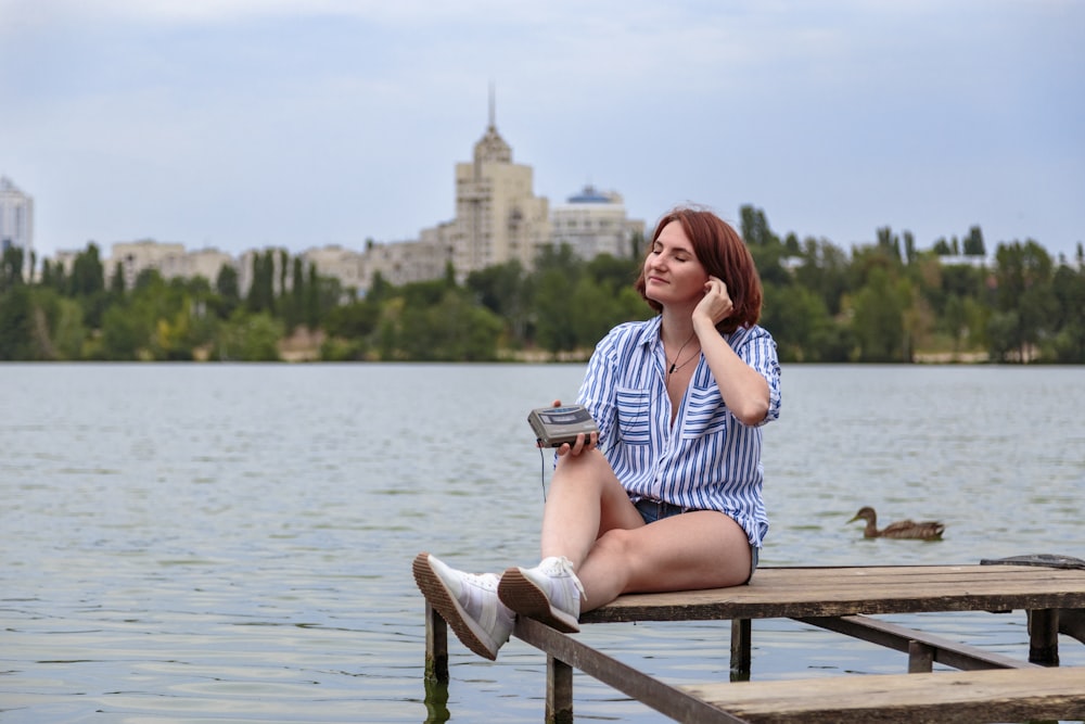 a woman sitting on a dock next to a body of water