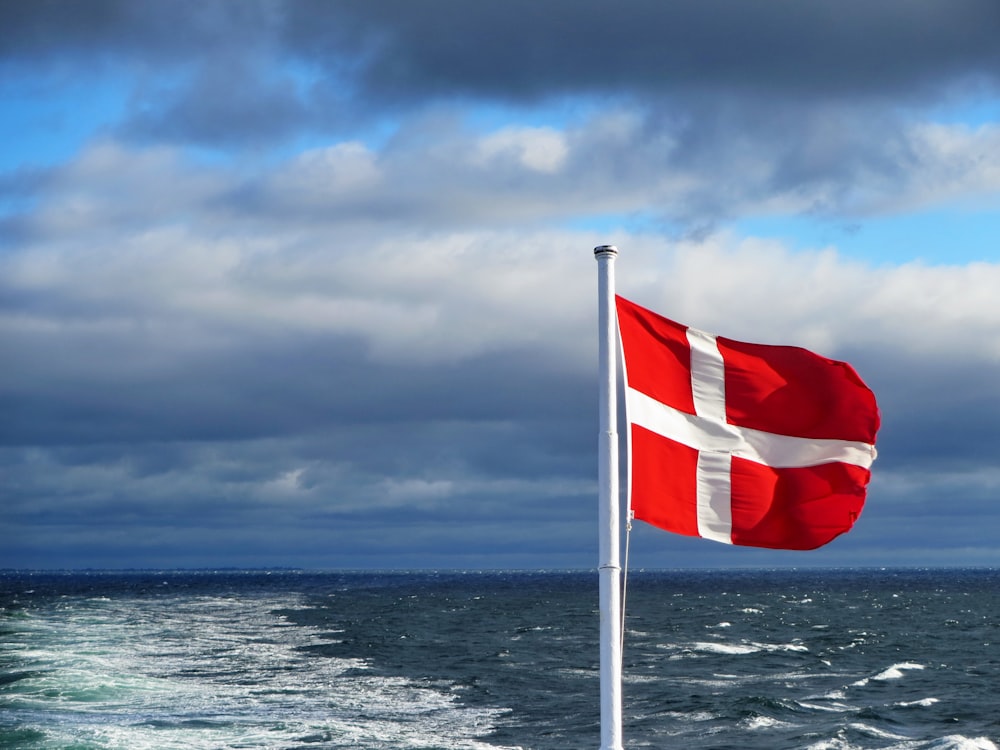 us a flag on flag pole near sea under cloudy sky during daytime