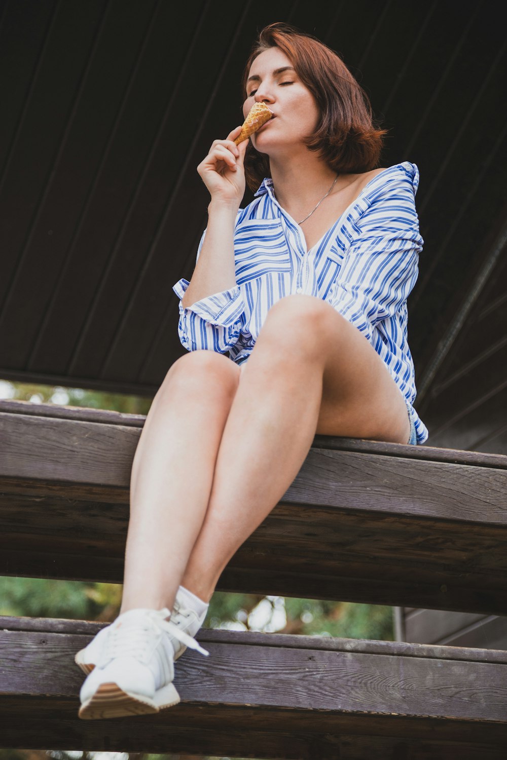 woman in white and blue stripe dress sitting on brown wooden bench