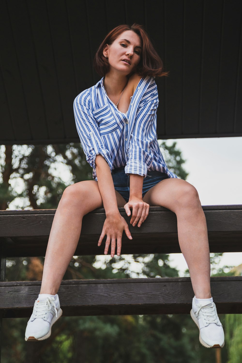 woman in blue and white stripe dress shirt sitting on black wooden bench