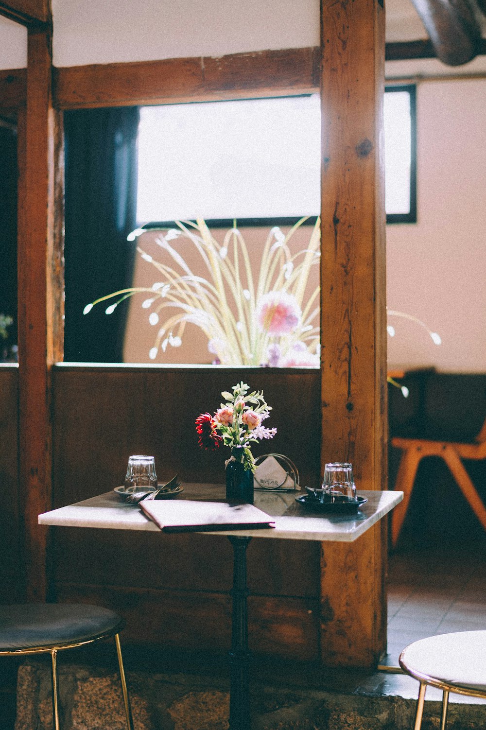 weiße und rosa Blumen in klarer Glasvase auf braunem Holztisch