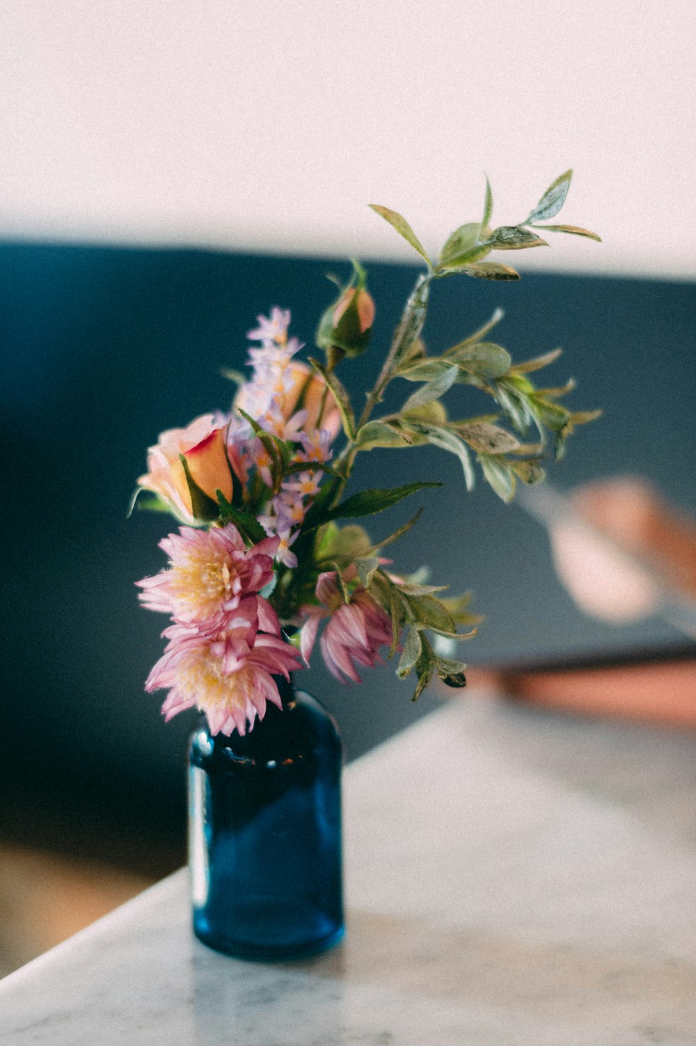 pink and yellow flowers in green glass vase