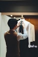 Young Italian tailor meticulously taking measurements of an elegantly dressed client in a classic atelier setting.