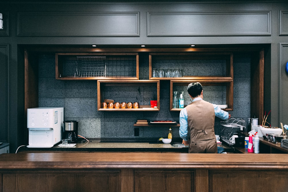 man in white dress shirt standing in front of counter