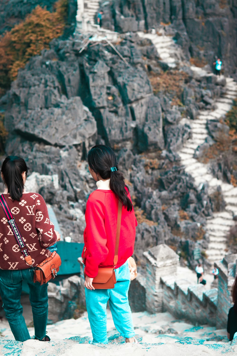 woman in red jacket standing near rock formation during daytime