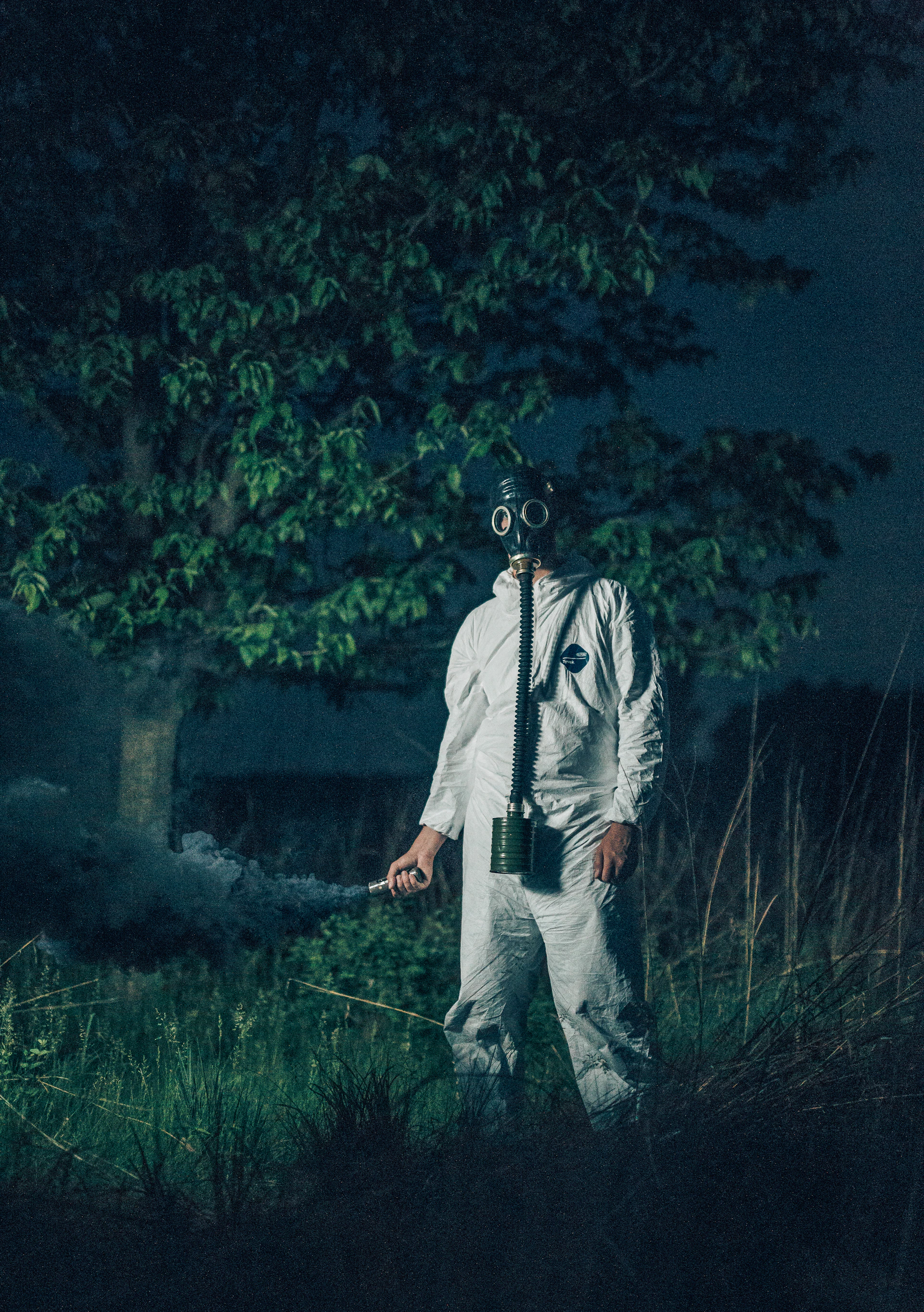 A professional technician wearing protective gear using a thermal fogging machine in a residential backyard at sunrise.