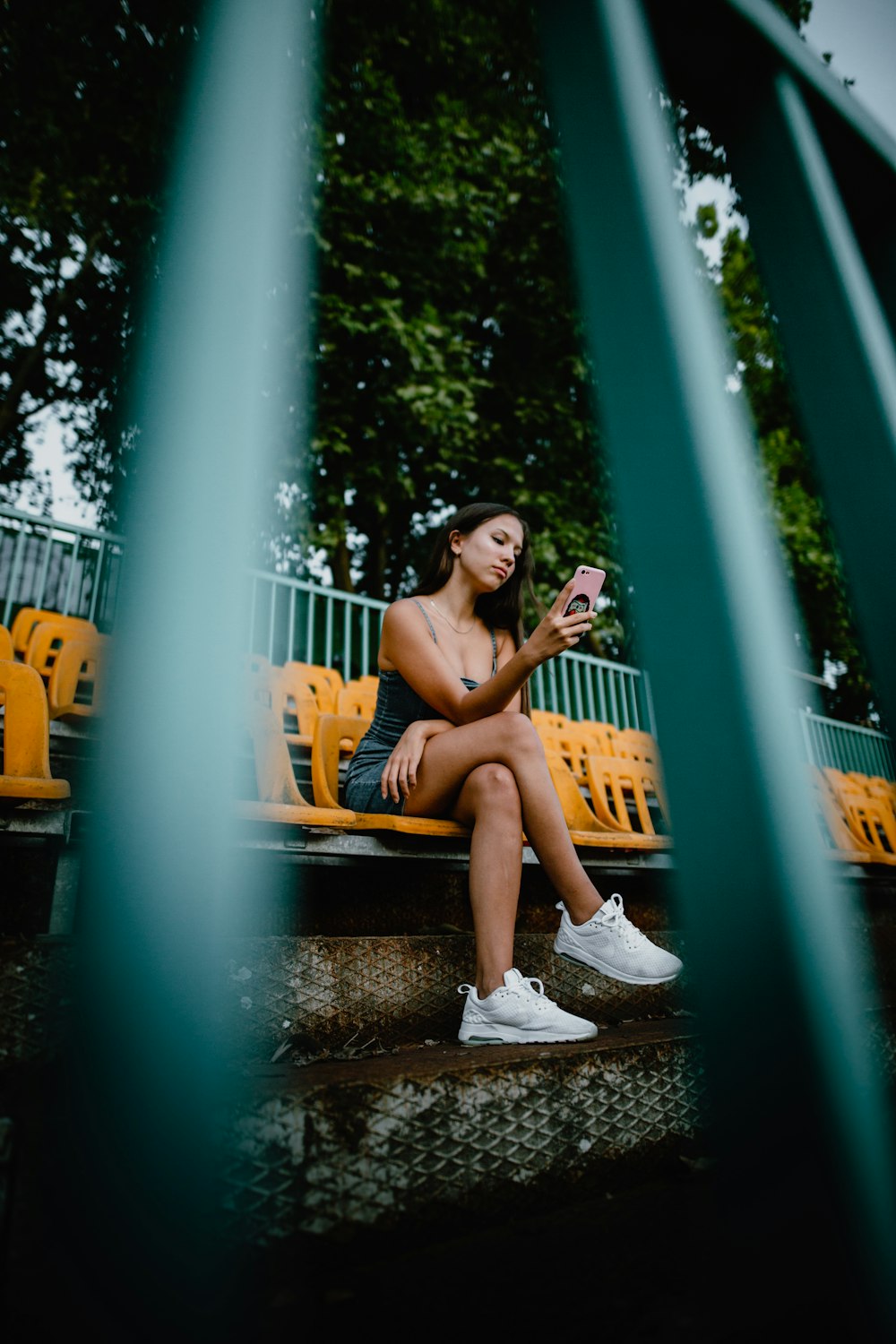 2 women sitting on black metal fence during daytime